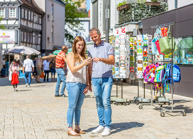 Zwei lachende Personen stehen in der Fußgängerzone in Nürtingen und schauen auf ihr Handy