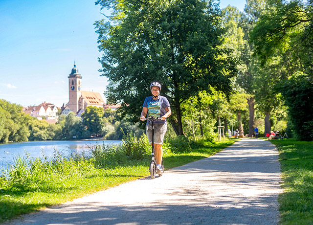 Mann fährt mit E-Roller durch die Landschaft